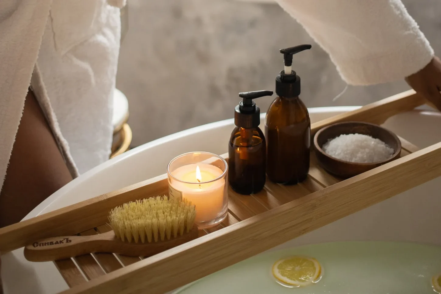 Person in a bathrobe holding a tray with spa products